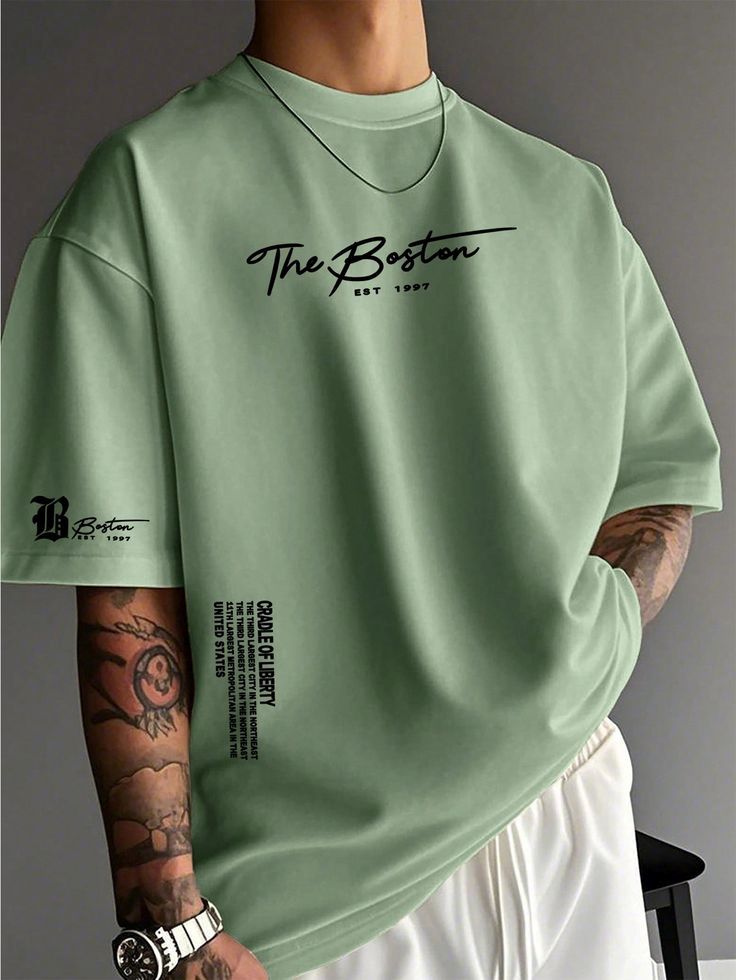 Men's oversized mint green T-shirt featuring "The Boston" graphic print on the chest, sleeve, and lower front, with a relaxed fit for casual streetwear.
