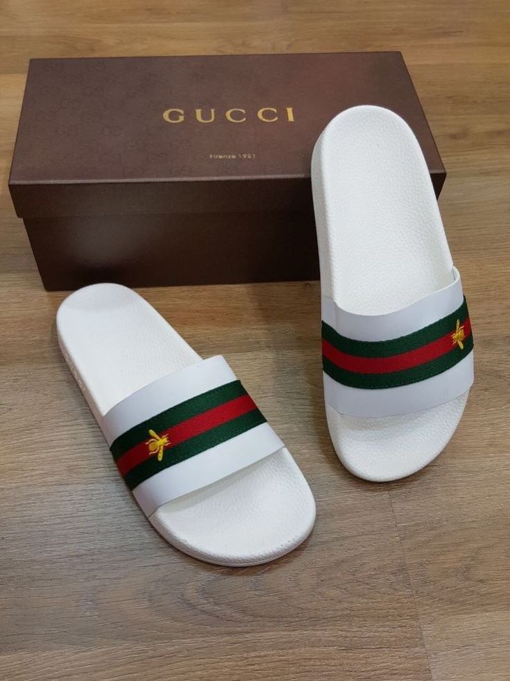 White casual slide sandals with green and red striped straps and embroidered bee detail.